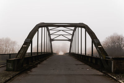 Footbridge in foggy weather against sky during winter