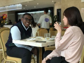 Portrait of smiling man sitting with friend in restaurant