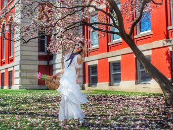 Woman standing by tree against building