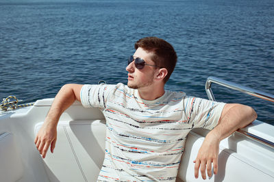 Young man sitting on boat in sea