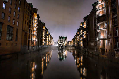 Canal amidst buildings in city at night