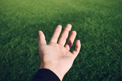 Close-up of hand against grass