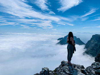 Full length of woman standing on rock against sky