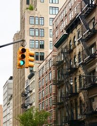 Low angle view of buildings in city and a green traffic light