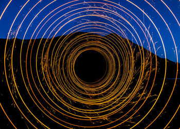 Directly below shot of light trails against sky at night