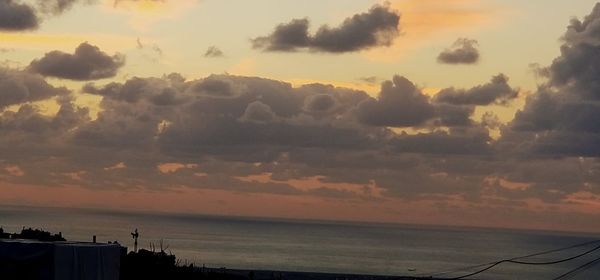 Scenic view of sea against dramatic sky during sunset