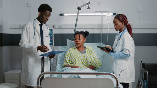 Doctors discussing with patient in ward at hospital