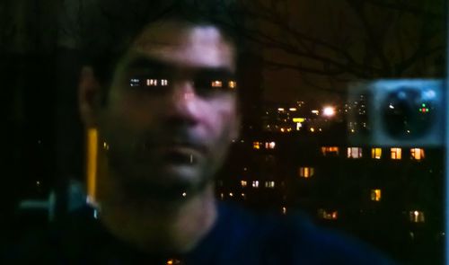 Portrait of man in illuminated city at night