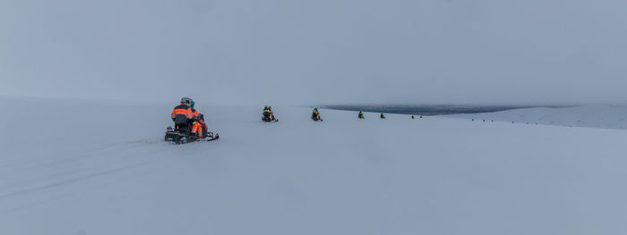 People snowmobiling on snowy glacier