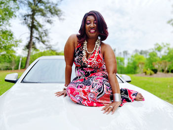 Portrait of smiling young woman sitting on car