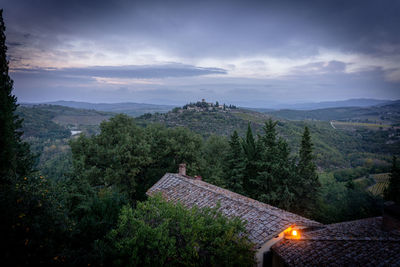 Trees and houses on mountain against sky