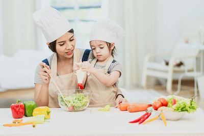 Midsection of woman holding ice cream in kitchen