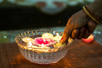 Close-up of hand holding tea light on table