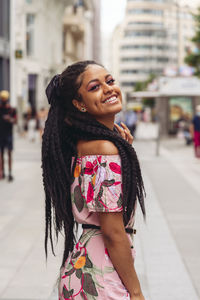 Portrait of smiling young woman standing on street in city