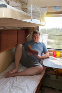 An adult man on a train with a book in his hand goes on vacation.