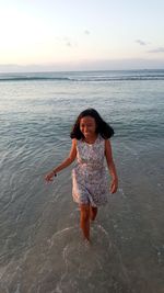 Rear view of woman standing at beach against sky