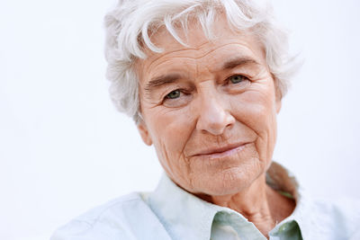 Close-up portrait of senior woman against white background