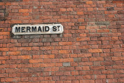 Close-up of arrow sign on brick wall