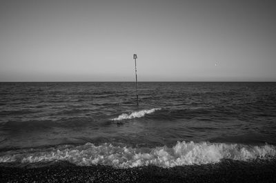 Scenic view of pole amidst sea against sky