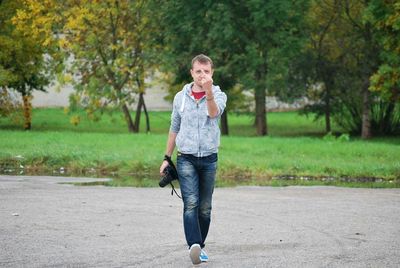 Portrait of man showing middle finger on street against trees