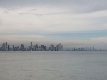 Sea and buildings in city against sky