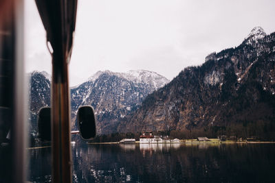 Cropped image of boat at lake against mountains during winter