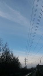 Low angle view of electricity pylon against cloudy sky