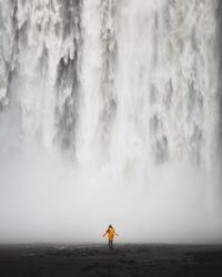 Rear view of woman standing against waterfall
