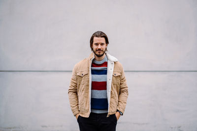 Portrait of young man standing against wall