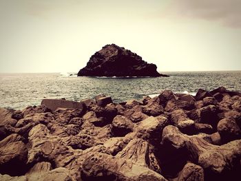 View of rocky beach against clear sky