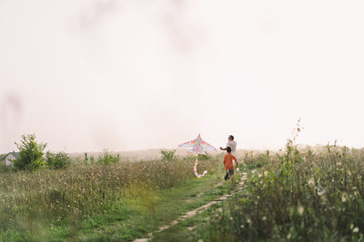 Happy family and children run on meadow with a kite in the summer on the nature.