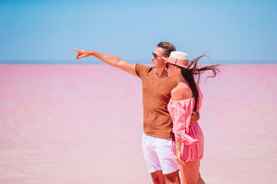 Woman with arms raised standing on beach