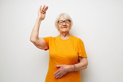 Portrait of smiling woman with arms raised against white background