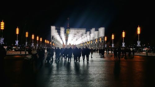 People at illuminated market against sky at night