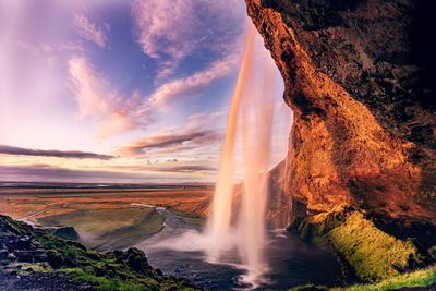 Scenic view of waterfall against sky during sunset