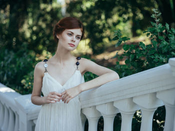 Young woman standing against white wall