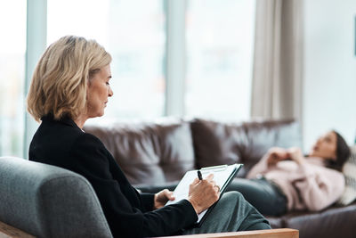 Young woman using laptop while sitting on sofa at home