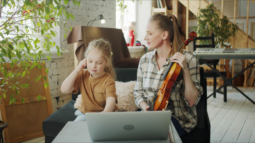 Mother teaching violin to daughter at home