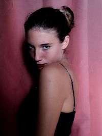 Portrait of woman standing against pink wall