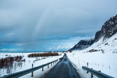 Road leading towards snow covered mountain against sky