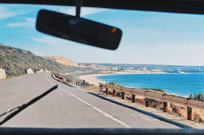 Car moving on road surrounded by sea