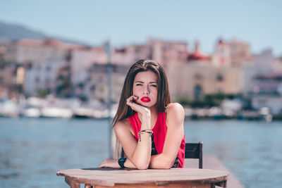 Portrait of woman sitting on pier over sea