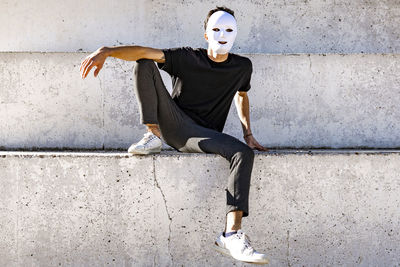 Man with white color face mask sitting on wall