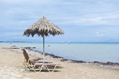 Deck chairs on beach against sky