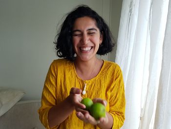 Smiling woman holding limes at home