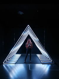 Portrait of woman standing against illuminated building