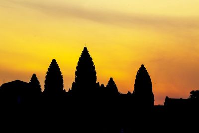 Silhouette of temple against buildings during sunset