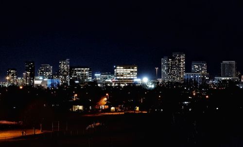 Illuminated cityscape against clear sky at night