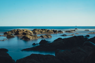 Scenic view of rocks in sea against clear sky