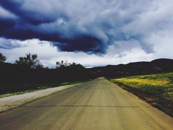 Country road against cloudy sky